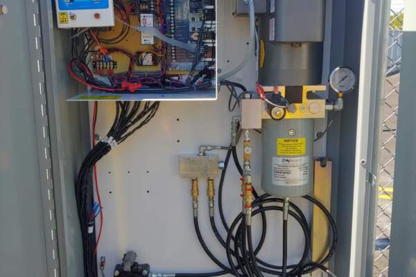 Inside a hydraulic gate operator showing the control board, pump and hydraulic lines